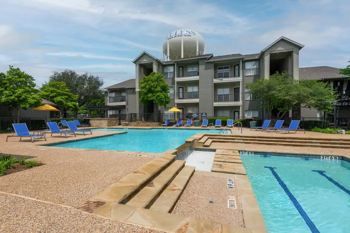 Resort-style swimming pool at Oak Park Apartments in Euless, TX, surrounded by lounge chairs and vibrant landscaping.