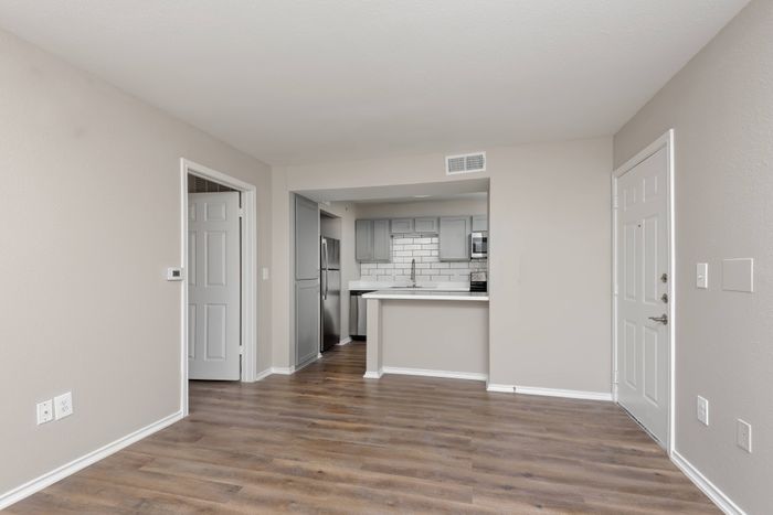 a large living room with hardwood floors and a great view of a modern kitchen