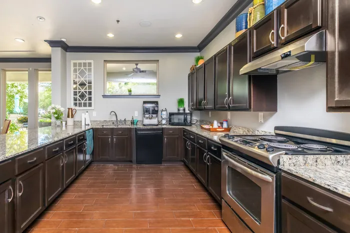 Modern community kitchen with granite countertops and stainless steel appliances in McDermott 55.