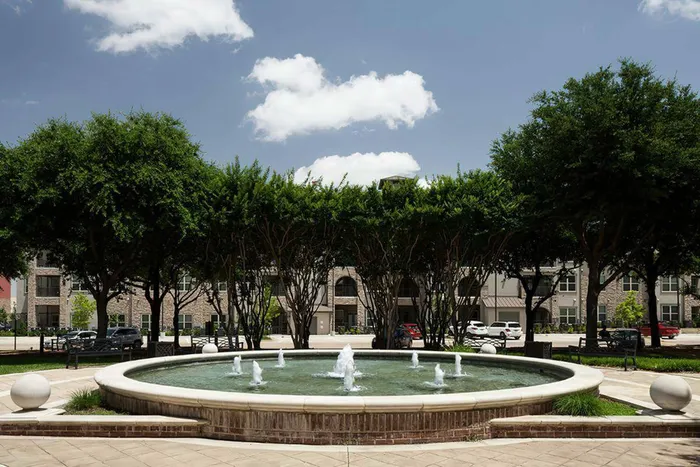 Front exterior view of McDermott 55 apartments with manicured landscaping in Plano, TX.