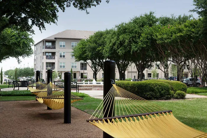 Relaxing outdoor hammock area surrounded by green lawns and trees at McDermott 55 in Plano, TX.