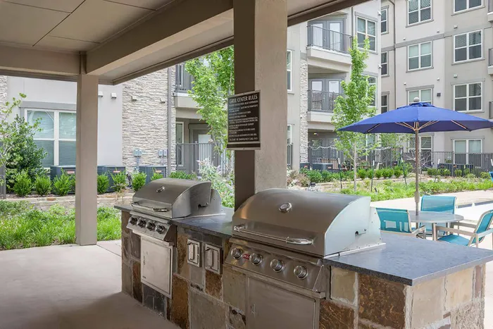 Outdoor grilling station with modern barbecue grills and shaded seating at McDermott 55.