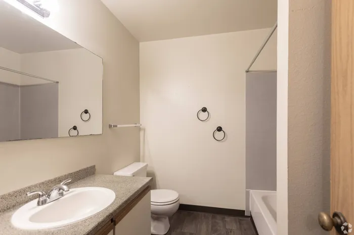 Sleek bathroom with a vanity, mirror, bright lighting, and a shower/tub combination at Winton Woods Apartments in Poulsbo, WA.