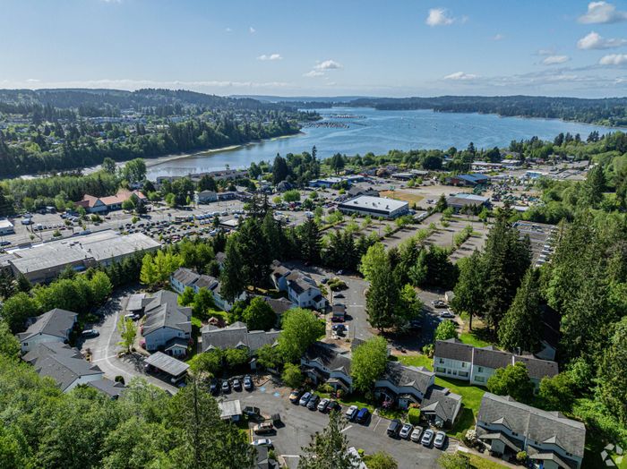 Bird's-eye view of Winton Woods Apartments, featuring apartment buildings, green spaces, and nearby forested areas in Poulsbo, WA.