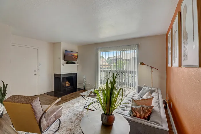Living room with a fireplace at Oak Park Apartments in Euless, TX, featuring cozy seating and large windows.
