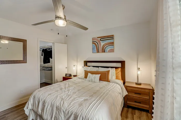 Elegant bedroom at Oak Park Apartments in Euless, TX, with a ceiling fan, cozy bedding, and spacious closet.