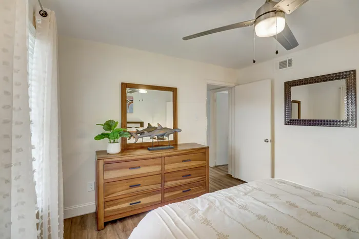 Bright bedroom with elegant wooden furniture and a ceiling fan at Oak Park Apartments in Euless, TX.