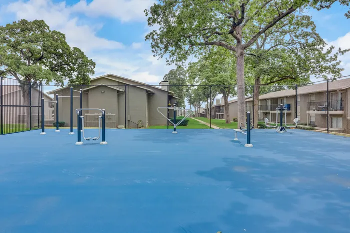 Outdoor fitness area at Oak Park Apartments in Euless, TX, with exercise equipment and a spacious layout.