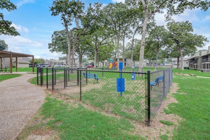 Spacious dog park at Oak Park Apartments in Euless, TX, with benches and open space for your furry friends to play.