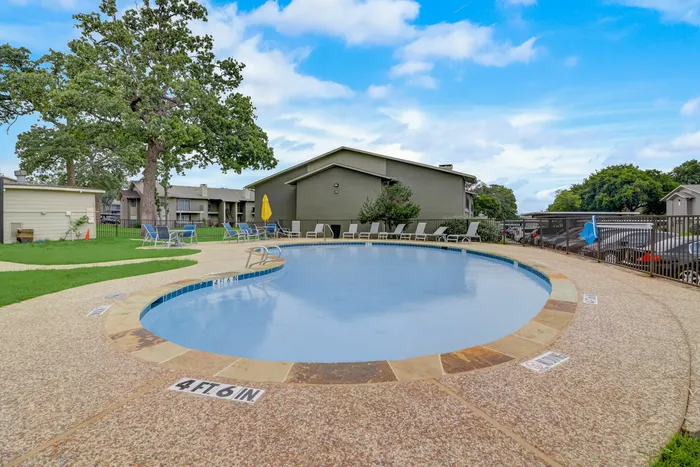 Resort-style swimming pool at Oak Park Apartments in Euless, TX, surrounded by lounge chairs and vibrant landscaping.