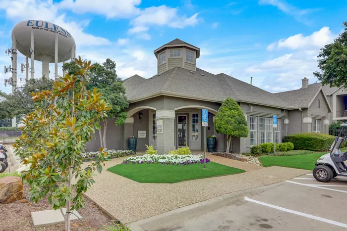 Charming leasing office at Oak Park Apartments in Euless, TX, surrounded by manicured landscaping and colorful flowers.