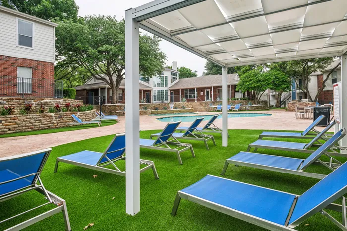 Relaxing outdoor lounge area with shaded seating and a view of the pool at a Plano, TX apartment community.