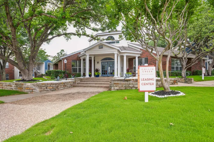 Charming leasing center with classic brick architecture and welcoming landscaping at an apartment community in Plano, TX.