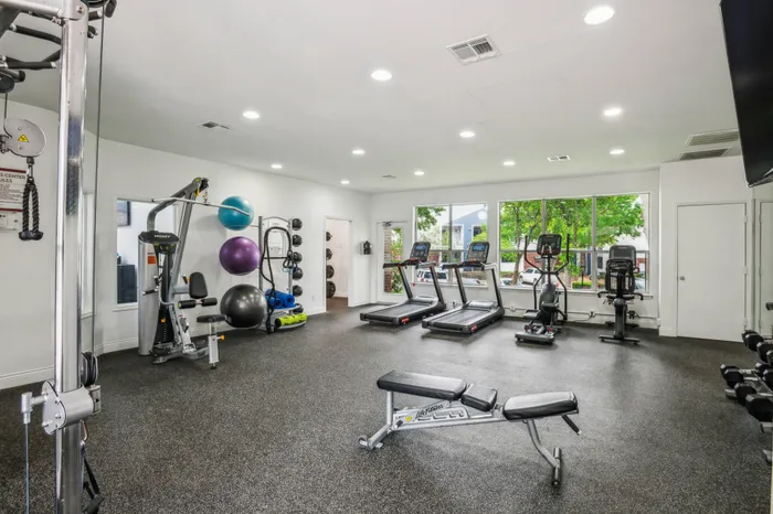 Modern fitness center with state-of-the-art equipment and natural light in a Plano, TX apartment community.