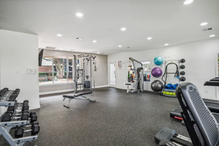 Modern fitness center with state-of-the-art equipment and natural light in a Plano, TX apartment community.