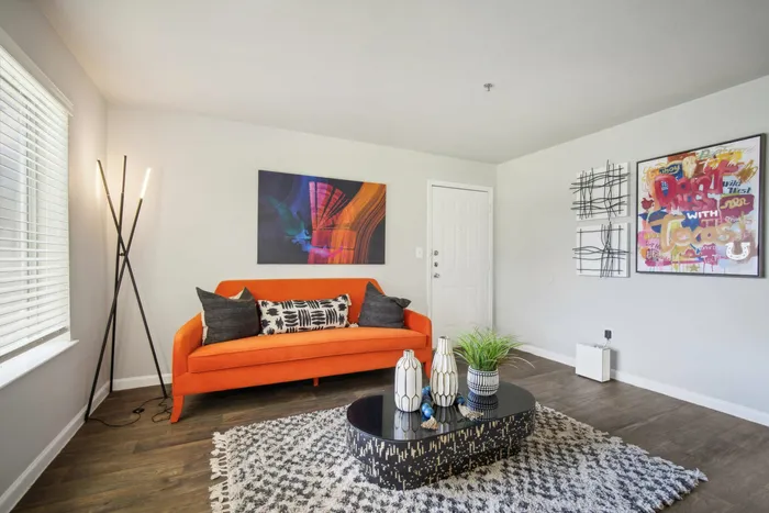 Stylish living area with an orange sofa, modern decor, and colorful accents at Ovation Apartments in Austin, TX.