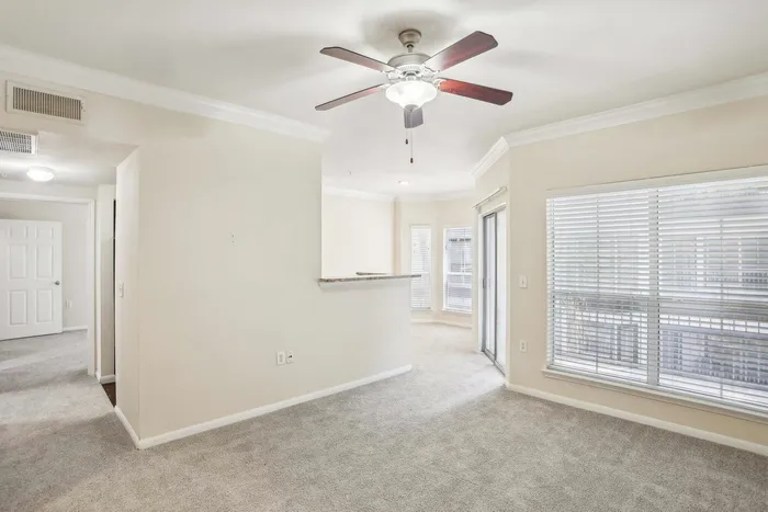 spacious living area with carpet and ceiling fan