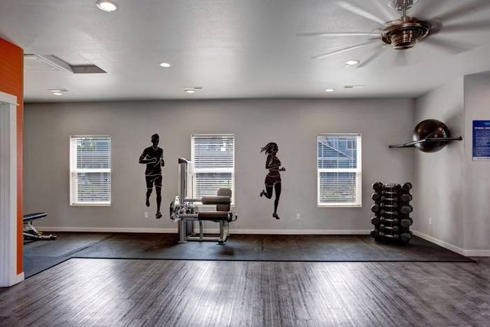 Fitness center with natural light, exercise equipment, and wall silhouettes at Navigator Villas in Pasco, WA.