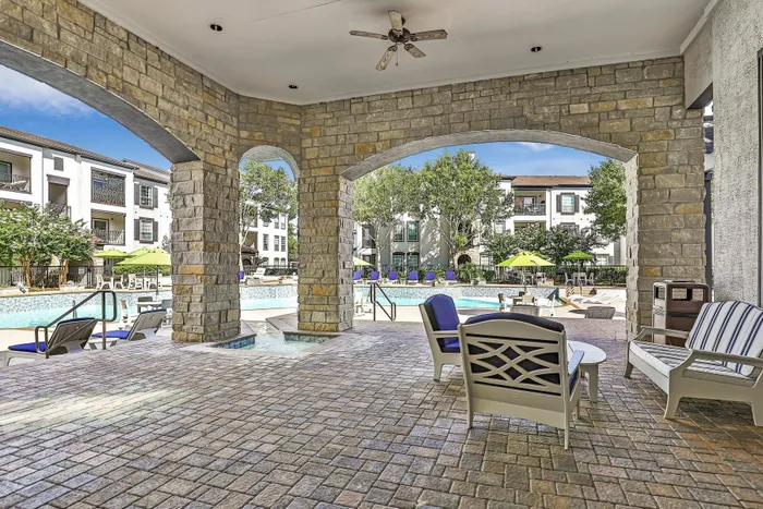 Covered patio with stone arches overlooking the pool area at Amalfi at Tuscan Lakes in League City, TX.