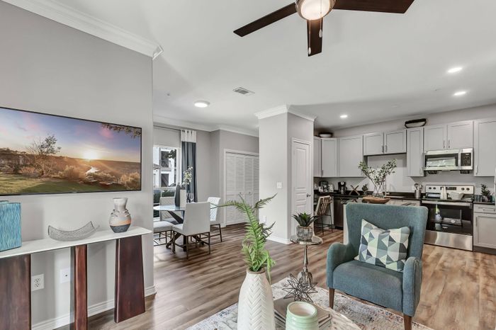 large room with furniture, light walls, and wall-to-wall hardwood flooring