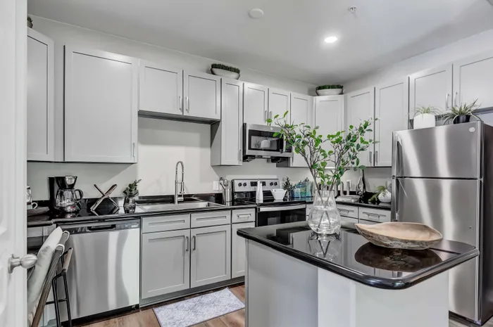 kitchen with large bar, dark counters, light cabinets, and stainless steel appliances