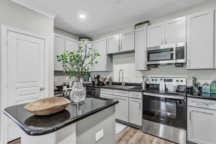 kitchen with large bar, dark counters, light cabinets, and stainless steel appliances