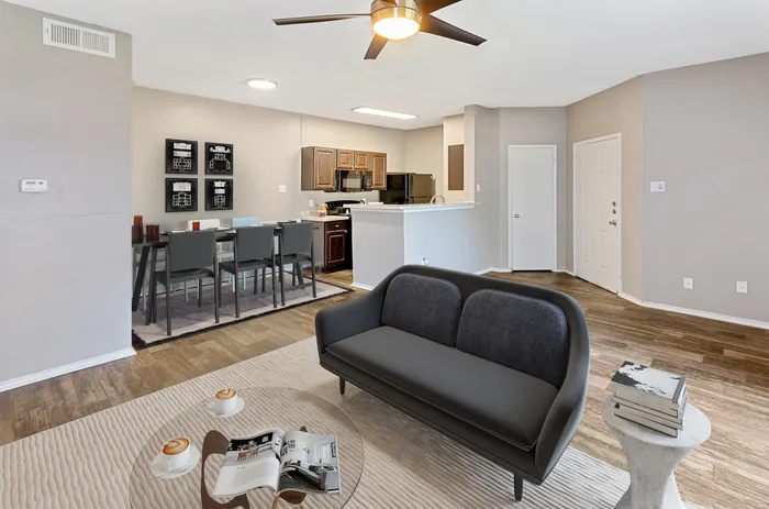 Modern open-concept living area with sleek furnishings, ceiling fan, and dining space in a Plano, TX apartment.