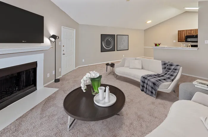 Elegant living room with a fireplace, cozy seating, and soft carpeting in a Plano, TX apartment.