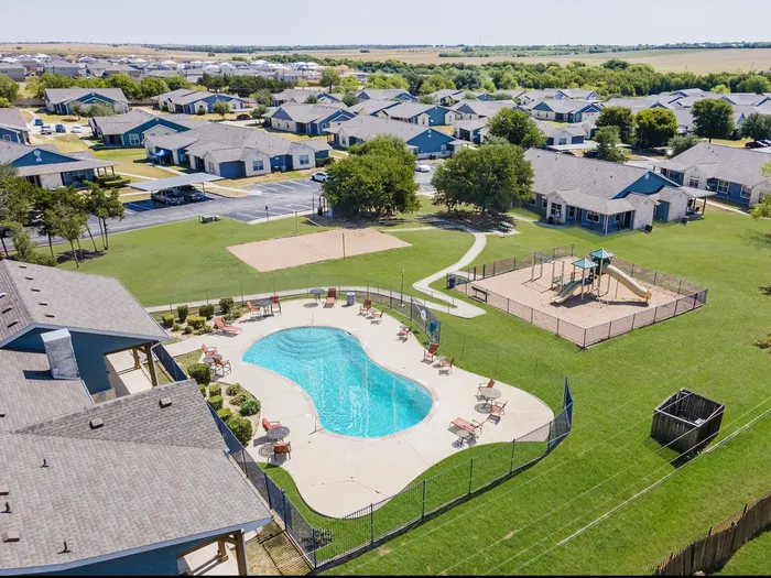 Aerial shot of pool, playground, and sand volleyball area at Crescent Village in Elgin, TX