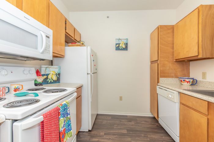 a kitchen complete with white appliances including a microwave, oven, dishwasher, and refrigerator