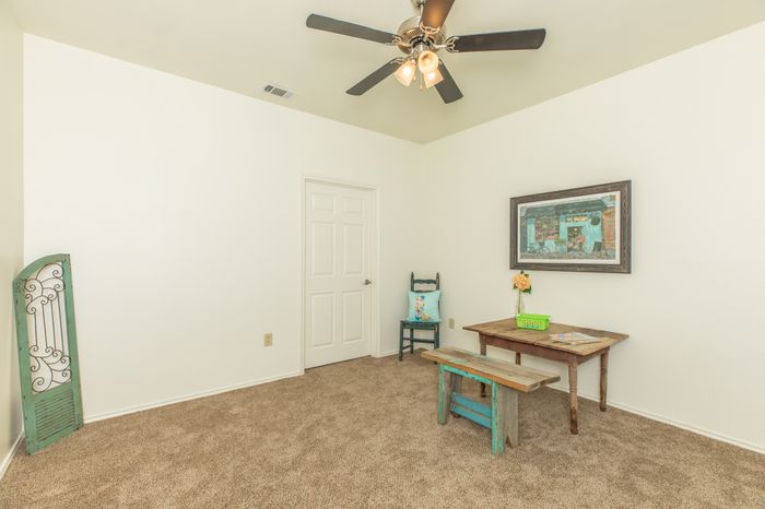 spacious bedroom with wall-to-wall carpeting and a ceiling fan