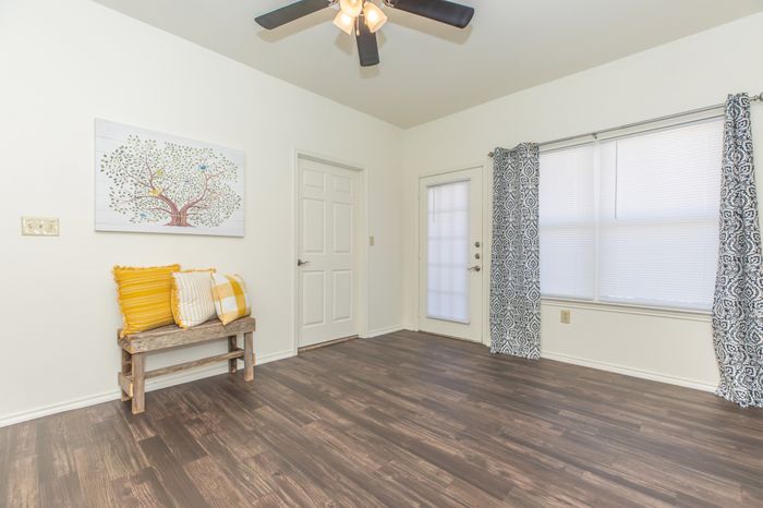 a room with hardwood floors, natural light, and a ceiling fan