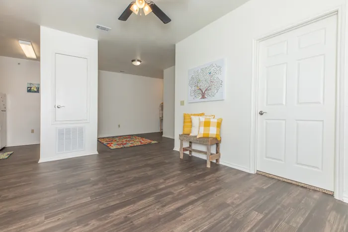 a room with hardwood floors, a ceiling fan, and is in view of a dining area and kitchen