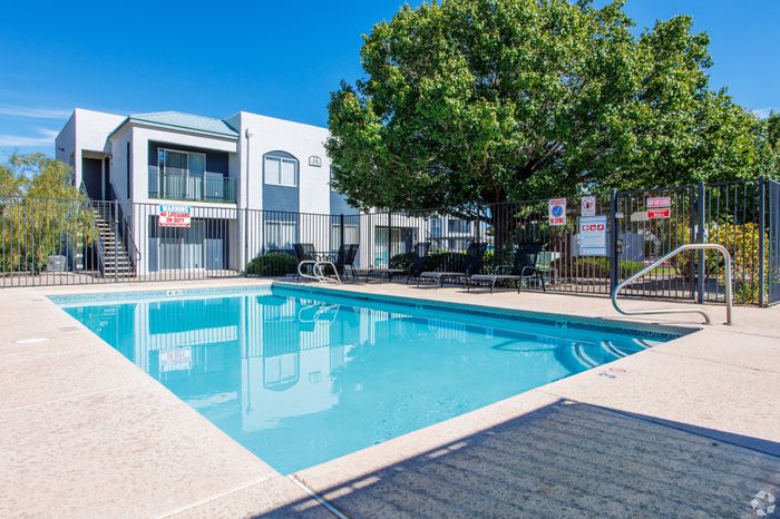 Beautiful outdoor pool area surrounded by seating and greenery at Lifestyles at Renaissance Apartments in Albuquerque, NM.