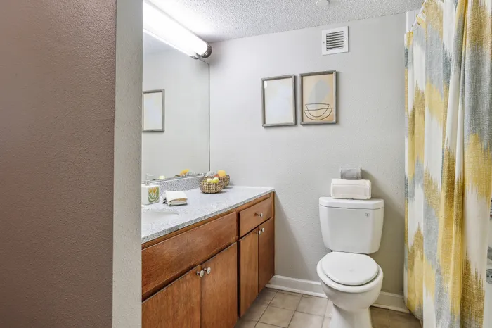 bathroom with good lighting, brown cabinets, and a white counter