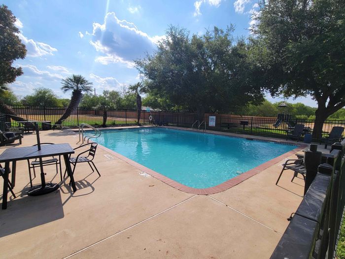 a clean blue pool surrounded by tables and chairs