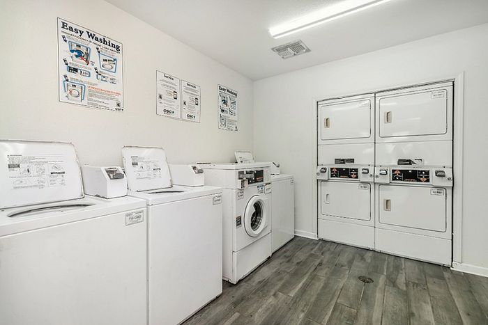 a room filled with washing machines and dryers, atop a wood floor
