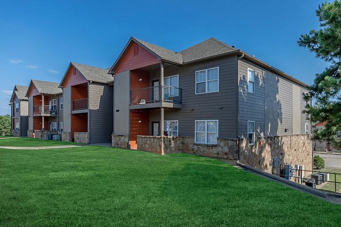 a two-story apartment building surrounded by luscious green grass