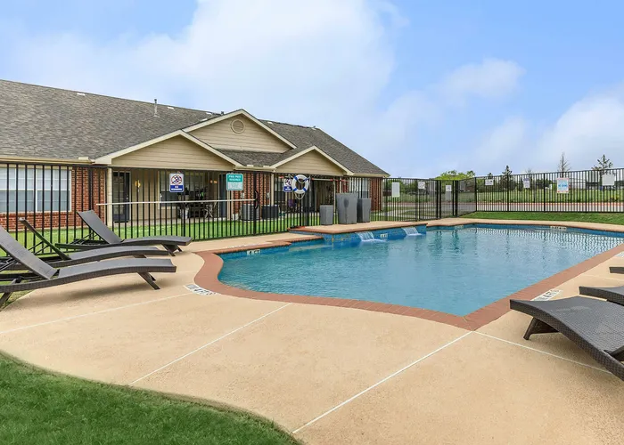 swimming pool with an expansive walkway and relaxing loungers surrounding the outside