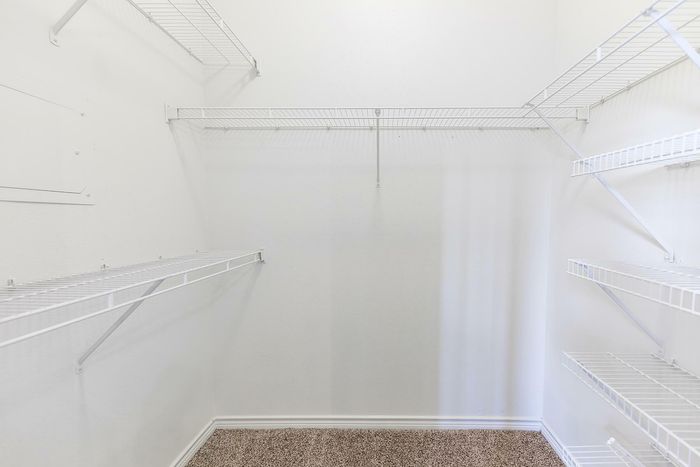 Walk-in closet with wire shelving and carpeted flooring at Willowbend Apartments in San Antonio, TX.