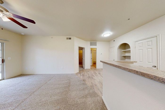 Bright living room with large windows, neutral walls, and wood-style flooring at Willowbend Apartments in San Antonio, TX.