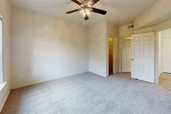 Bedroom with soft carpet flooring, a large window, and neutral-colored walls at Willowbend Apartments in San Antonio, TX.
