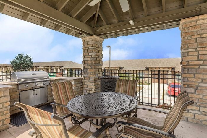 Covered outdoor dining area with BBQ grill and elegant seating at Arroyo Seco Villas in San Antonio, TX.