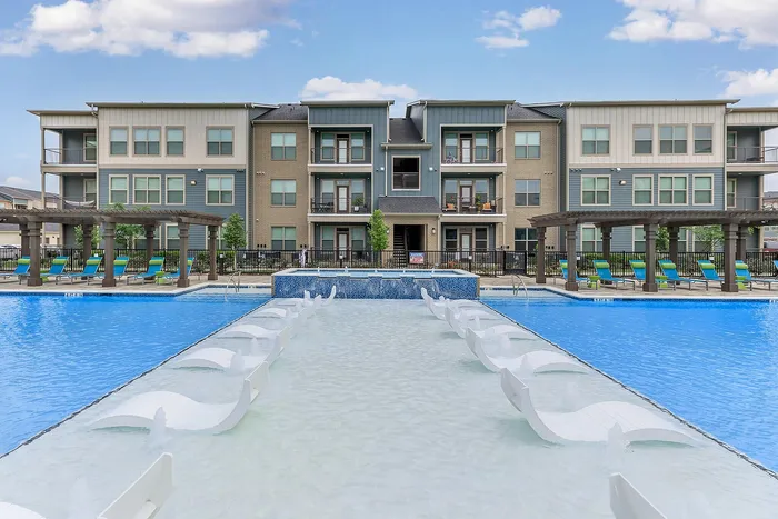Shallow water lounge area with built-in recliners at the resort-style pool at Cityscape Apartments in Houston, TX.