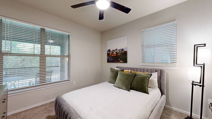 Cozy bedroom with a neutral color palette, stylish décor, and ceiling fan at The Woods of Five Mile Creek, Dallas, TX.