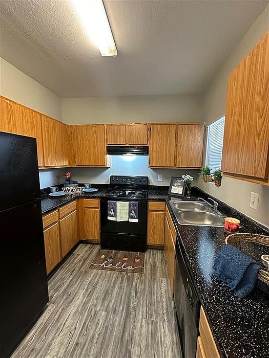 Spacious kitchen with wooden cabinetry, black appliances, and sleek countertops at Granada Place Apartments in Uvalde, TX.