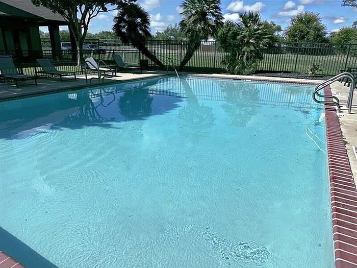 Sparkling outdoor pool with lounge chairs and lush surroundings at Granada Place Apartments in Uvalde, TX.
