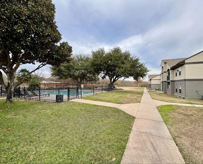 Well-maintained community grounds with a pool and shaded seating areas at Granada Place Apartments in Uvalde, TX.