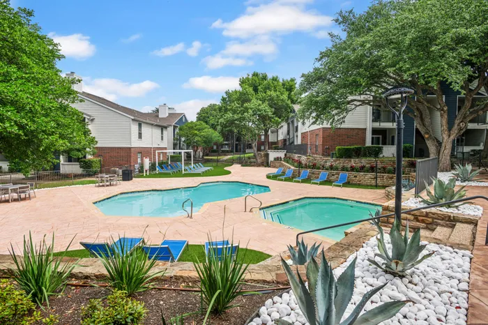 Serene outdoor pool area with lush landscaping and comfortable lounge chairs at a Plano, TX apartment community.