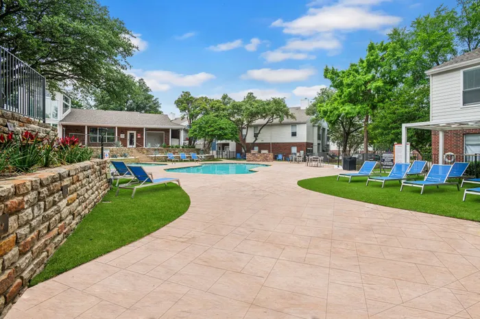 Expansive poolside patio with lush greenery and ample seating at a Plano, TX apartment community.